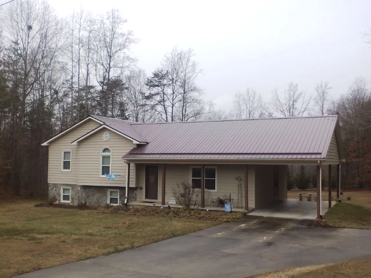 Burgundy metal roof on a tan split level home with an attached carport in Glen Oaks
