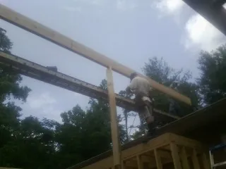 Carpenter setting a ridge beam over a new addition frame — Ice Dam Removal by Roofing Brothers in Glen Oaks