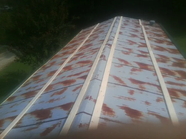 Rusted metal roof panels with new wood purlins before replacement — Storm Damage Roof Repair in Glen Oaks by Roofing Brothers