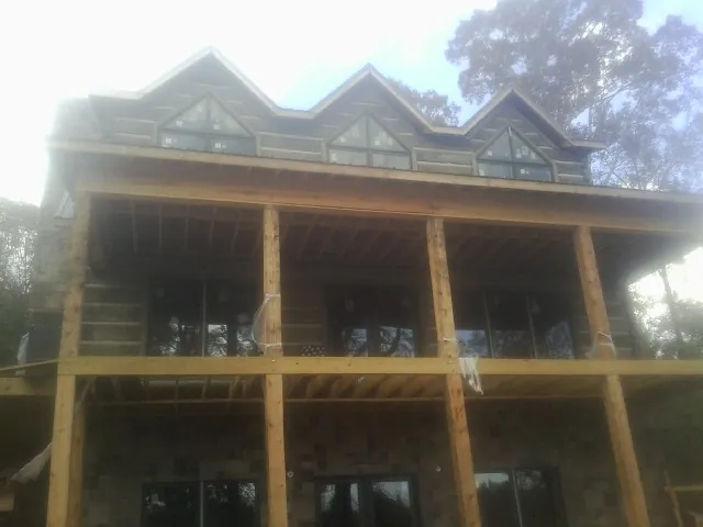 Dormers and porch framing on a large log home under construction — Roof Coating work by our crew in Glen Oaks