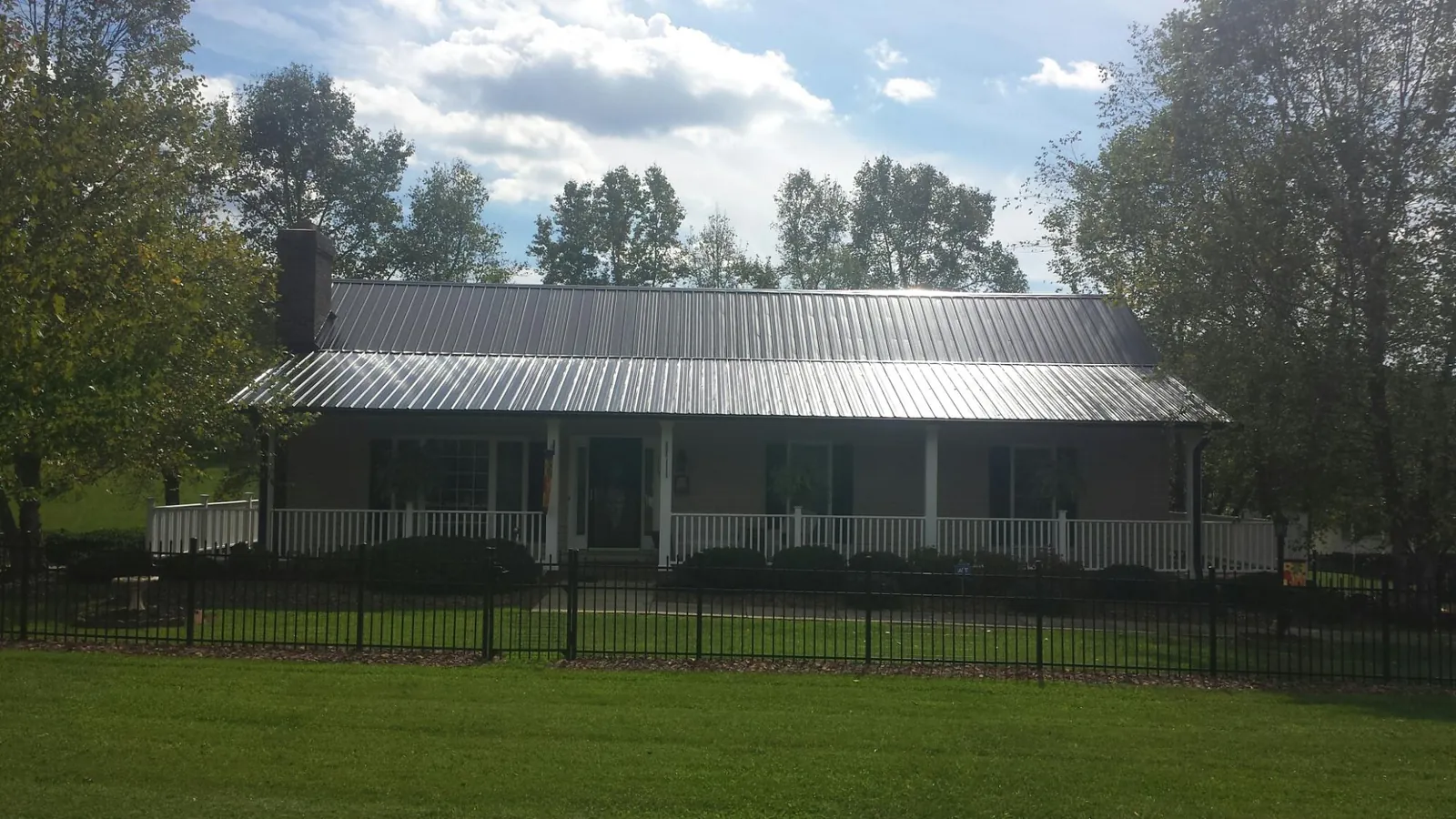 Gray metal roof on a brick ranch with a full width front porch — Gutter Guard Installation work by our crew in Glen Oaks