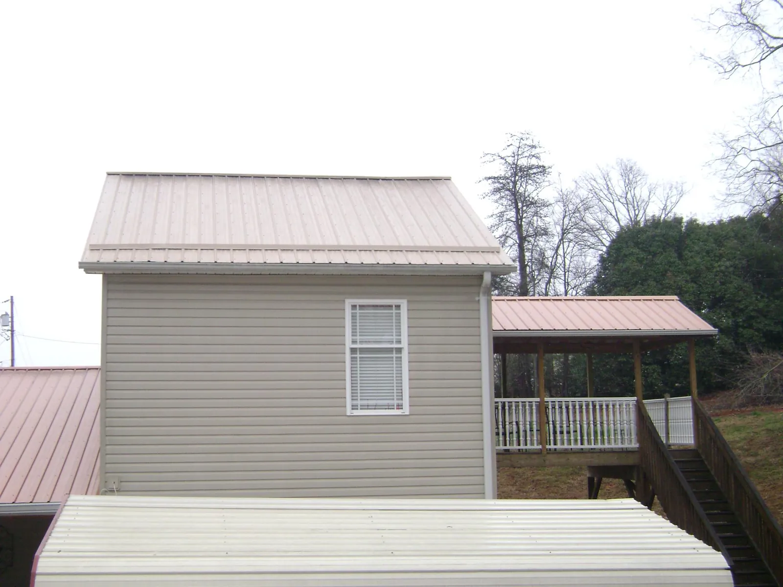 Tan metal roofs on a two story addition and attached porch, from a Roof Replacement job in Glen Oaks